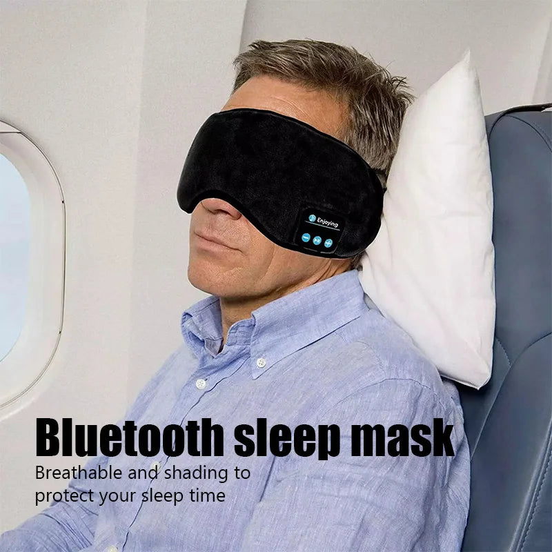Man wearing black bluetooth sleep headphones with eye mask resting on airplane seat with pillow