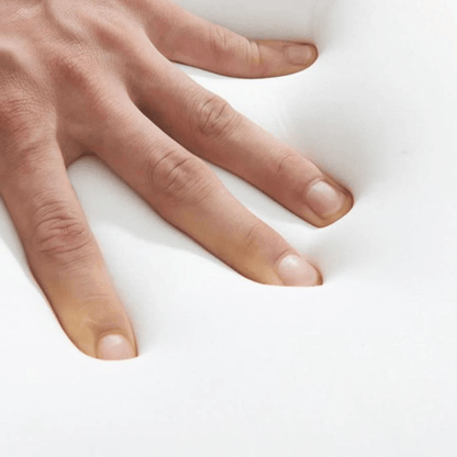 Hand pressing soft white memory foam on AI pain relief pillow showing its cushioning comfort