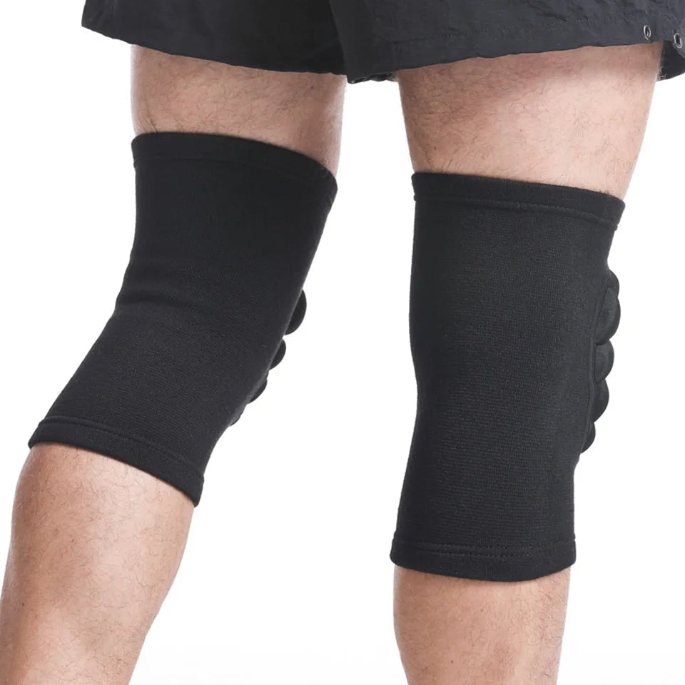 Black sports knee pads for joint support worn on both knees by a person in black shorts
