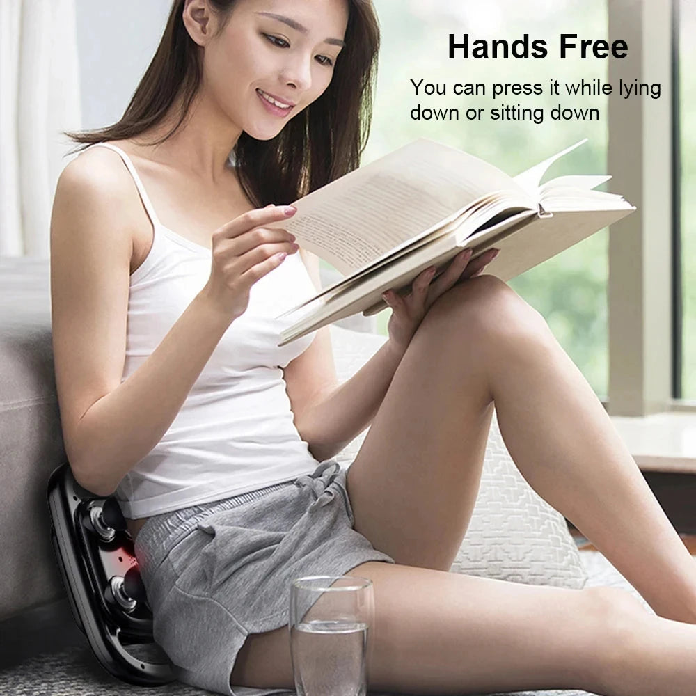 Woman using Zorelie deep tissue massage gun for pain relief hands free while reading a book at home