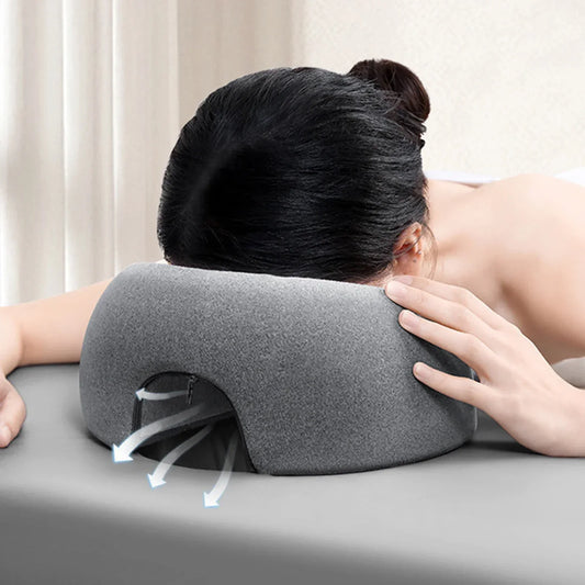 Person using a gray ergonomic memory foam headrest designed for comfortable face-down support