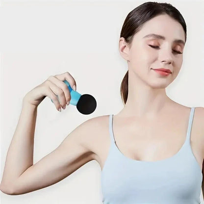 Woman using handheld mini muscle massage gun on shoulder for muscle relief and relaxation