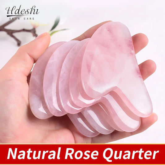 Hand holding multiple pink natural stone gua sha facial tool made of rose quartz for skincare