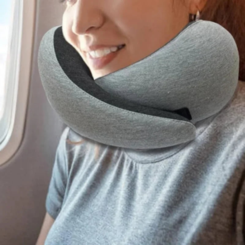 Woman wearing a gray memory foam travel neck pillow while sitting on an airplane
