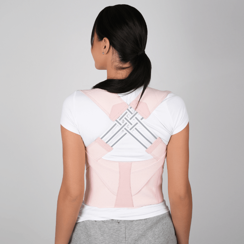 Back view of woman wearing Zorelie adjustable posture corrector in light pink over white shirt