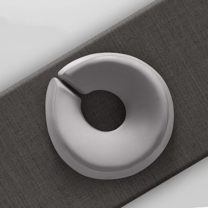 Gray ergonomic face rest pillow for massage on a dark textured mat for comfortable head support